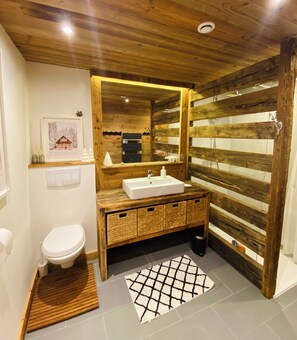 Ein Badezimmer mit einem Holzlagerflächen, einem weißen Waschbecken, einem Spiegel und einer Toilette.