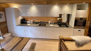 A modern kitchen with white cabinets, a wooden ceiling, and a built-in oven. - Luxury apartment at the foot of the slopes- (Arâches-la-Frasse)