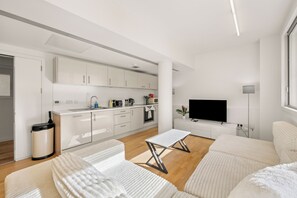 A modern, minimalist living space with a kitchen, dining area, and a flat-screen TV. - Spacious Fitzrovia Apt with Central A/C (London)
