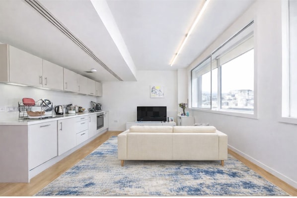 Eine moderne Wohnung mit Küche, Wohnbereich und großen Fenstern.