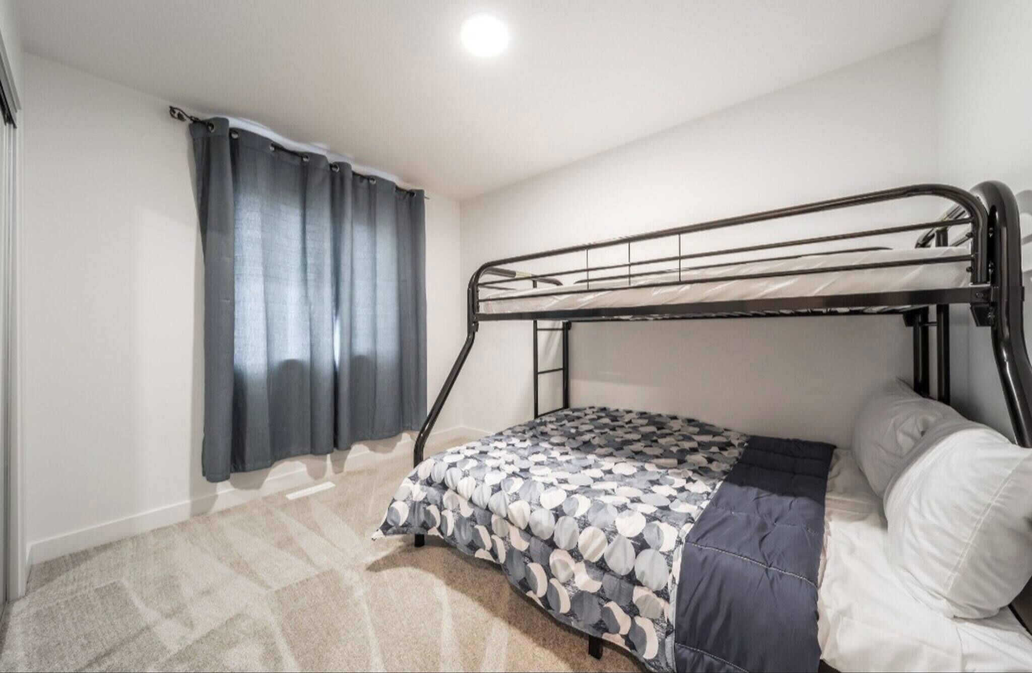Een eenpersoonsbed met een metalen frame, een bed met een patroon erop en een wit kussen.