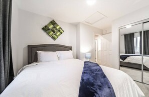 Een hotelkamer met een groot bed, een bedlamp, een spiegel en een garderobe.