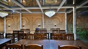 Un comedor con mesas y sillas de madera, candelabros y una pared de vidrio con vistas.