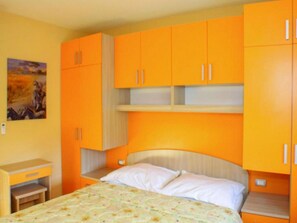 A bedroom with a bed, orange cabinets, and a small desk. - 14-guest Holiday Home in Vrgorac (Vrgorac)