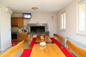 Ein Essbereich mit Holztisch und Stühlen, einem Kamin und einem Fernseher darüber.
