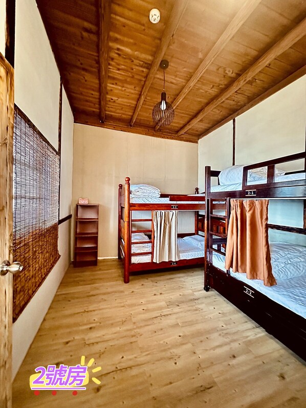 Una habitación con literas de madera, un pequeño estante y una lámpara colgante.
