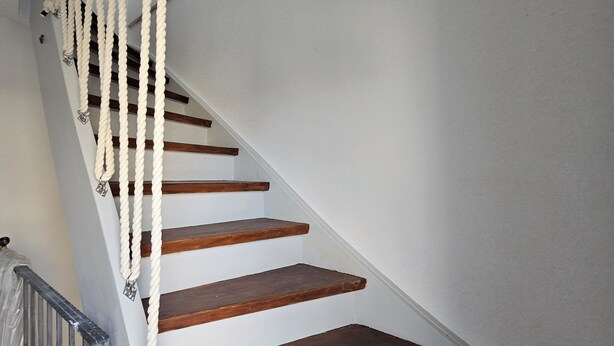 Eine Treppe mit Holzboden und Seilhandläufen.