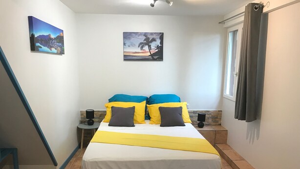 Ein Schlafzimmer mit einem Bett, zwei Nachttischen, einem Fenster mit Vorhängen und zwei Wandbildern.