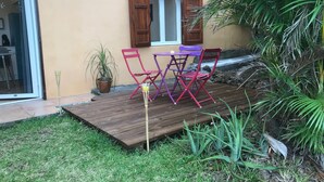 Eine Terrasse mit Holzboden, einem Tisch und zwei Stühlen.