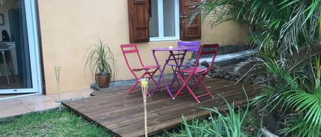 Une terrasse avec une plateforme en bois, une table et deux chaises.