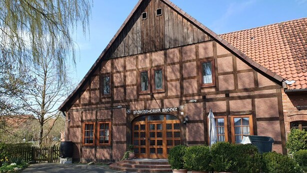 A traditional wooden building with a steeply pitched roof and a sign reading "Hotel Krika Wodice".