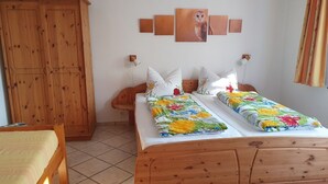 A room with two wooden beds, a wooden wardrobe, and a wall-mounted owl painting.