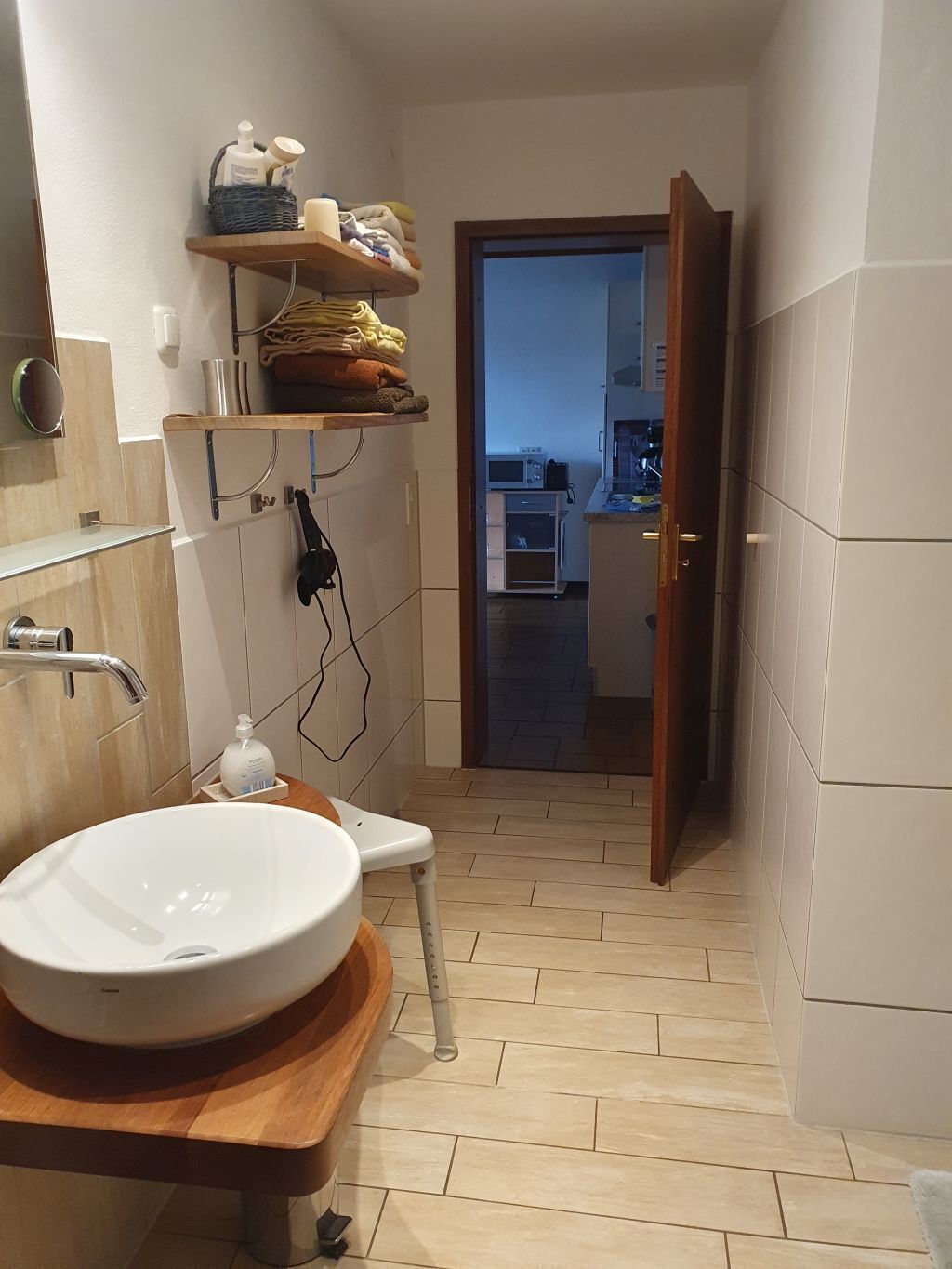 A bathroom with a wooden vanity, a white sink, and a shower area.