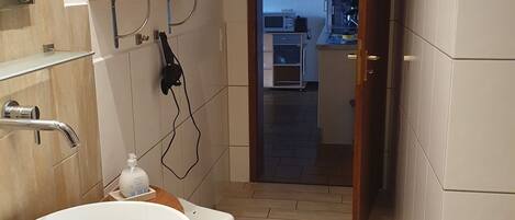 A bathroom with a wooden vanity, a white sink, and a shower area.