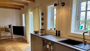 Una cocina moderna con una isla grande, suelo de madera y ventanas amplias.