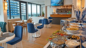 Comedor de hotel con bufé, distribución de mesas y un bar.