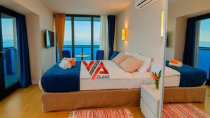 Una habitación de hotel amplia con una cama grande, una mesita y vista al océano.