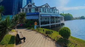 Un hotel frente al agua, con un edificio moderno y una estructura tradicional, un sendero pavimentado y una masa de agua.