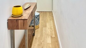A narrow hallway with a wooden console table, a yellow pot, and a patterned cushion. - Superb Studio teletravail - Rooftop Paris (Saint-Ouen-sur-Seine)