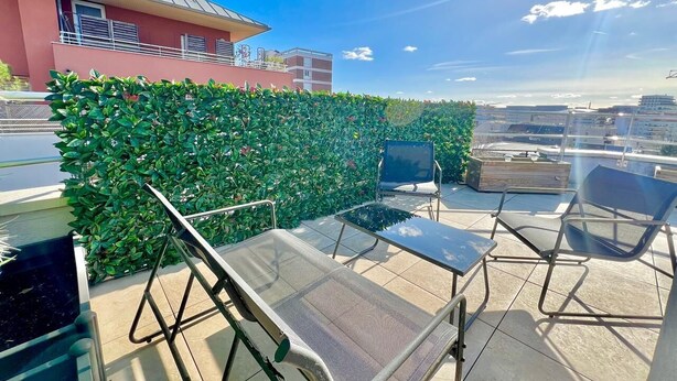 A rooftop terrace with a glass table, metal chairs, and a green hedge wall. - Superb Studio teletravail - Rooftop Paris (Saint-Ouen-sur-Seine)