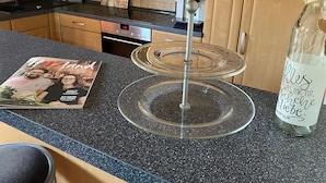 A kitchen counter with a magazine, a glass cake stand, and a bottle with a label. - Holiday Apartment De Gruusse (Mildenau)