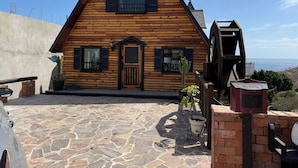 A wooden cabin with a clock, a stone-paved entrance, and a view of the ocean. - Beautiful Ocean View Cabin by k38 (Playas de Rosarito)