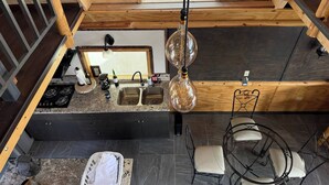 A kitchen with a double sink, stove, and a hanging light fixture. - Beautiful Ocean View Cabin by k38 (Playas de Rosarito)