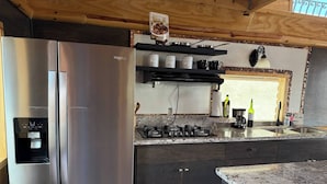 A modern kitchen with a stainless steel refrigerator, a water dispenser, a gas stove, and a coffee machine. - Beautiful Ocean View Cabin by k38 (Playas de Rosarito)