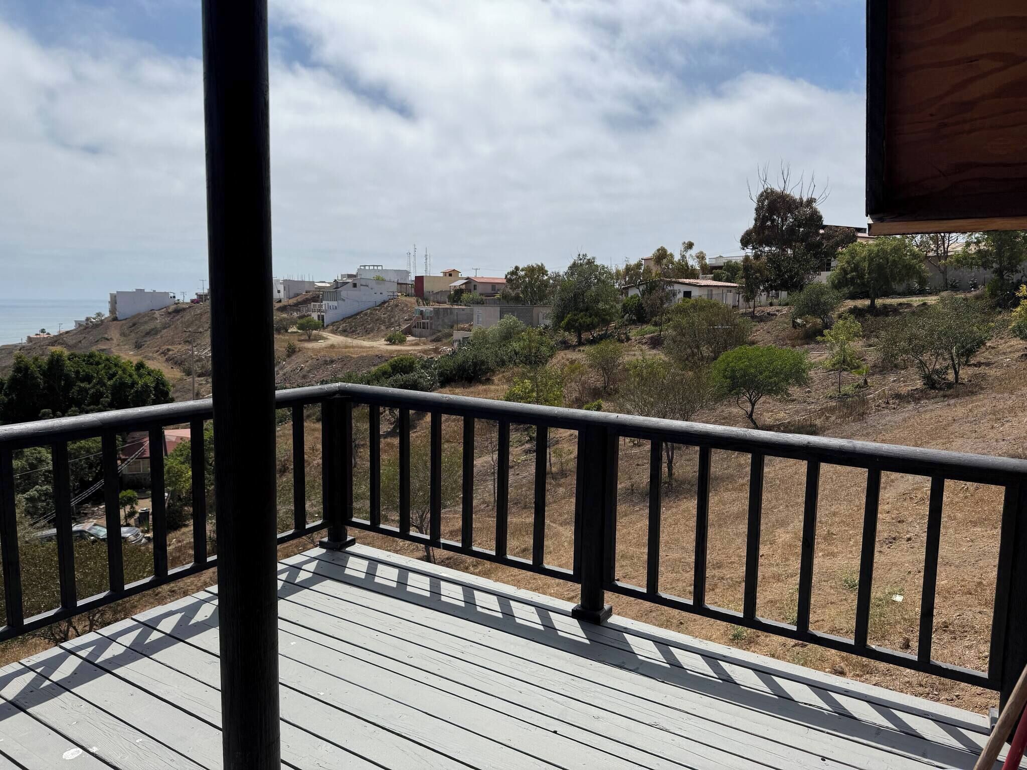 A wooden deck with a railing overlooking a residential area with houses and trees.