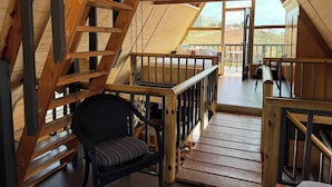 A wooden interior with a loft bedroom, a staircase, and a balcony with a view. - Beautiful Ocean View Cabin by k38 (Playas de Rosarito)