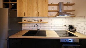 A modern kitchen with wooden cabinets, a stainless steel refrigerator, a black sink, and a built-in oven. - Tinj Rustic Holiday Home for 8 (Benkovac)