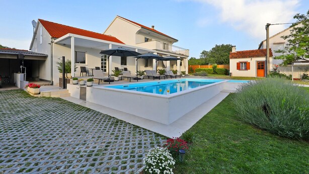 A modern house with a swimming pool, outdoor seating, and a well-maintained garden. - Tinj Rustic Holiday Home for 8 (Benkovac)