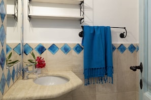 Ein Badezimmer mit Waschbecken, Spiegel, Handtuchhalter mit blauem Handtuch und dekorativen blau-beigen Fliesen.