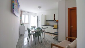 Un espacio habitable compacto con comedor, kitchenette y una puerta que da a otra habitación.