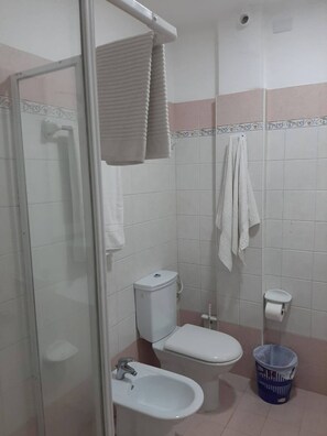 Un baño pequeño con inodoro, bidé y cabina de ducha de vidrio.