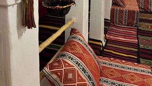 Habitación tradicional con textiles estampados, una cesta colgante y un banco de madera.