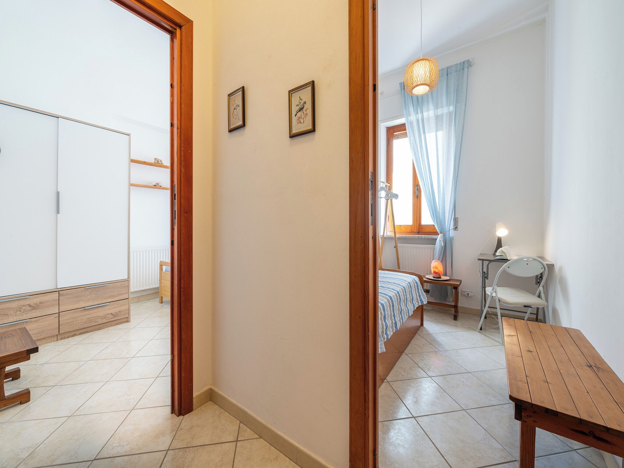 Ein Schlafzimmer mit Bett, Schreibtisch, Stuhl und einem Fenster mit Vorhängen.