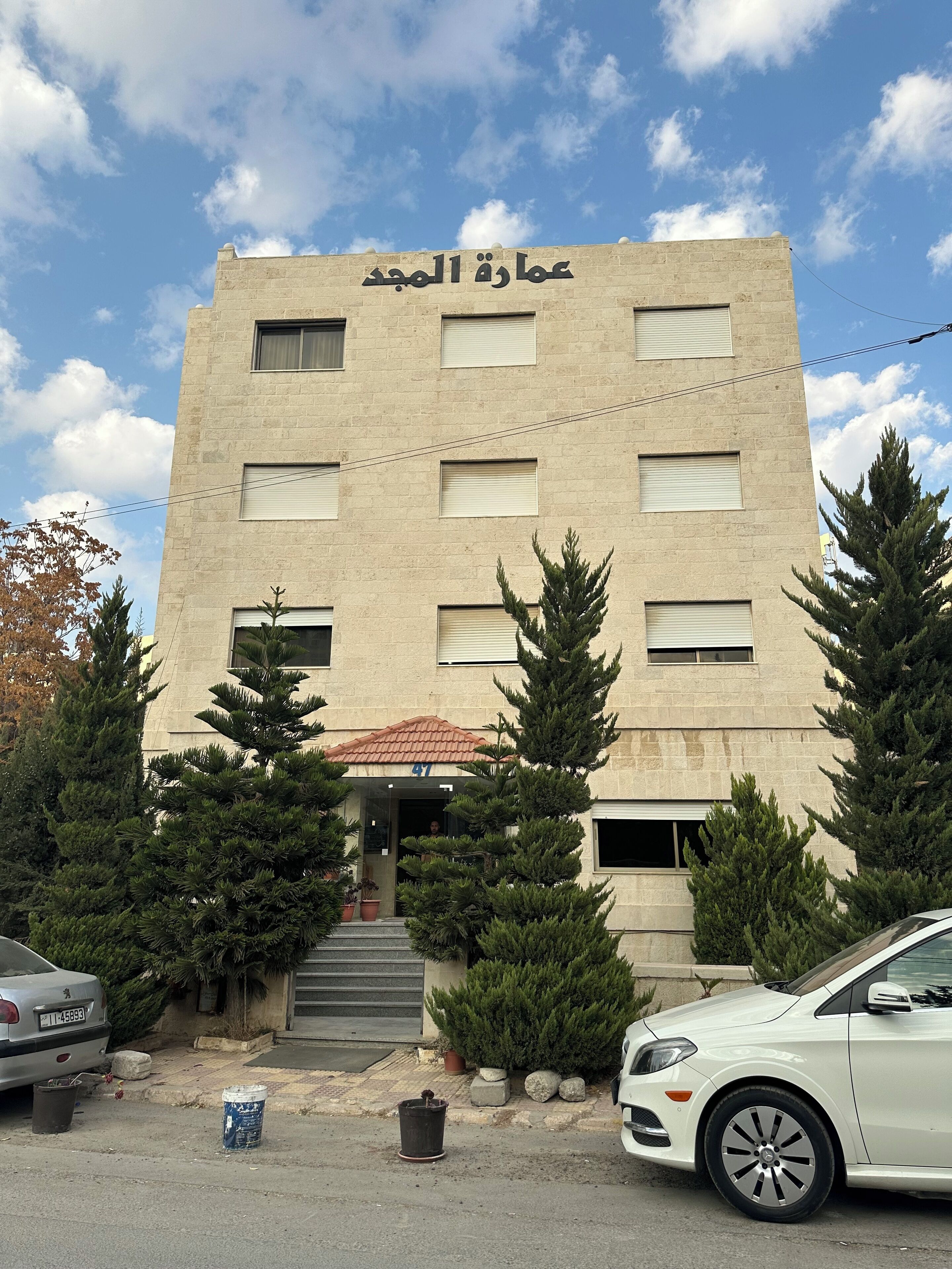 A building with a sign in Arabic, multiple windows, and a red-tiled roof.