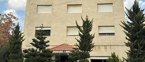 A building with a sign in Arabic, multiple windows, and a red-tiled roof.