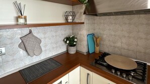 Cozinha moderna com bancadas de madeira, fogão a gás e armários brancos.