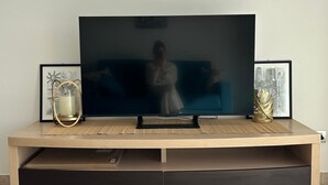 Uma unidade de entretenimento moderna com uma televisão de tela plana, um sofá e objetos decorativos.
