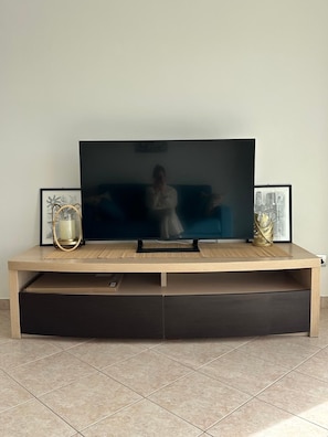 Ein modernes Unterhaltungselement mit Flachbildfernseher, einer Couch und Dekorationselementen.