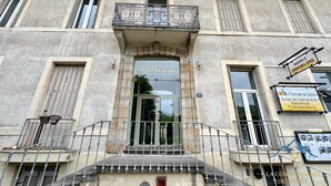 Un edificio con un cartello che riporta la scritta "LES AMBASSADEURS" e un balcone con ringhiera in ferro battuto.