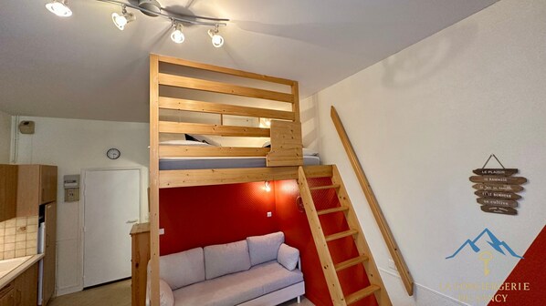 A bunk bed with a ladder, a sofa, and a wall-mounted sign. - Mezzanine Spa Stay for 4 (La Bourboule)