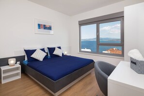 A modern bedroom with a bed, bedside tables, a desk, and a large window offering a sea view. - Charming Villa With Heated Pool (Posedarje)