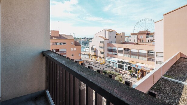 Un balcón con vista a un puerto deportivo y una noria.