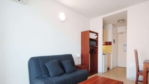 Un espacio habitable compacto con un sofá azul oscuro, una mesa de centro de madera y un armario de madera.