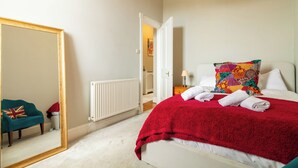 A hotel room with a bed, a large mirror, a radiator, and a teal armchair. - Gorgeous 2BDR with Unique Character in Edinburgh (Edinburgh)