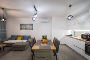 Ein moderner Wohnbereich mit Essplatz, Küchenzeile und einer Couch mit Kissen.
