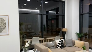 Een moderne woonkamer met een witte eettafel, een beige bank en twee bijzettafeltjes.